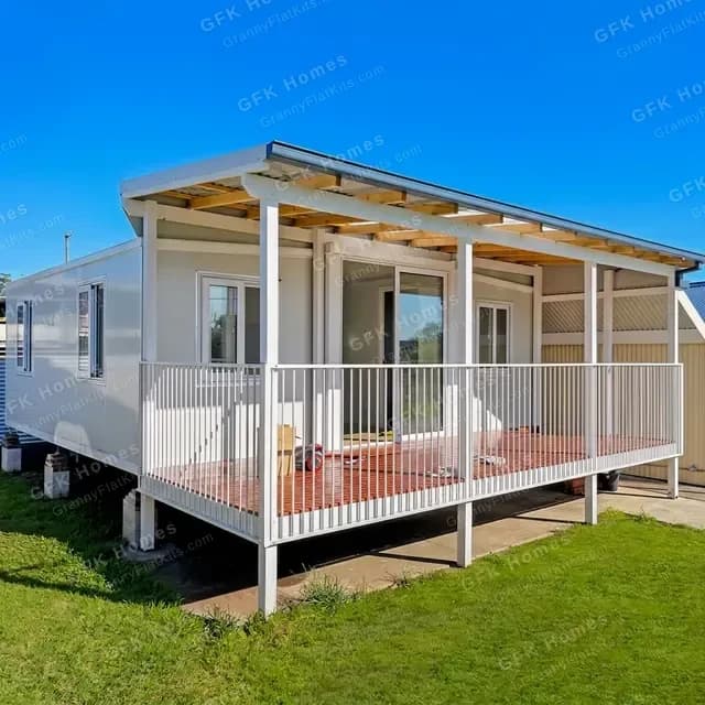 Expanded container home with covered patio, white metal railing, and timber decking